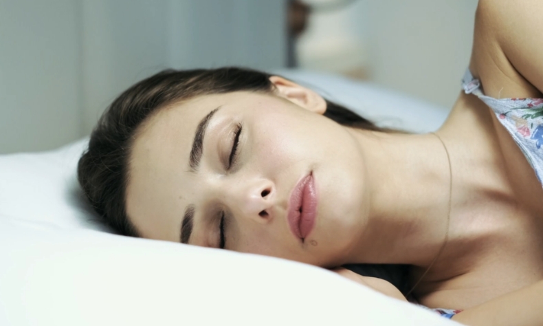 Žena mirno spava na jastuku u krevetu