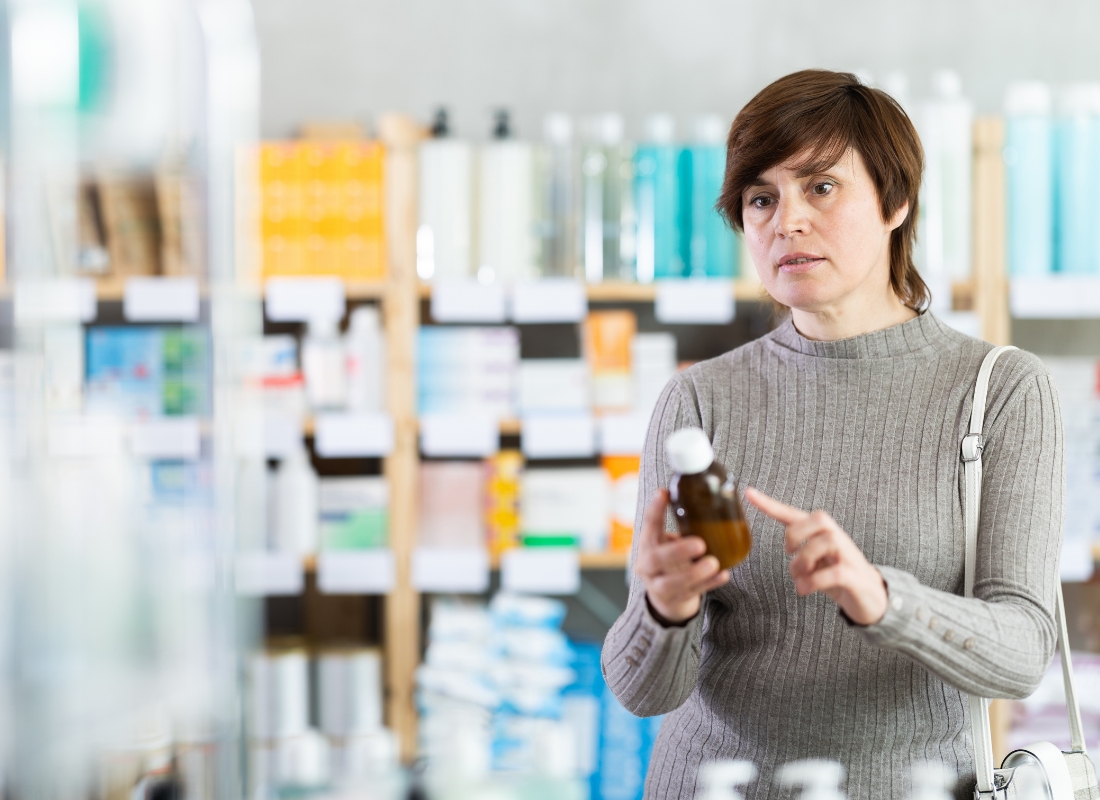 žena stoji u apoteci i bira sirup