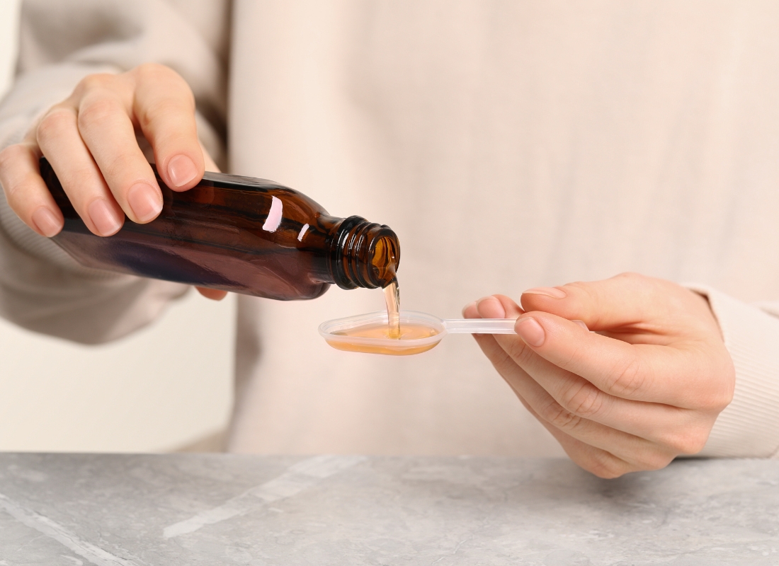 prikaz ženske osobe koja sipa sirup u plastičnu kašičicu